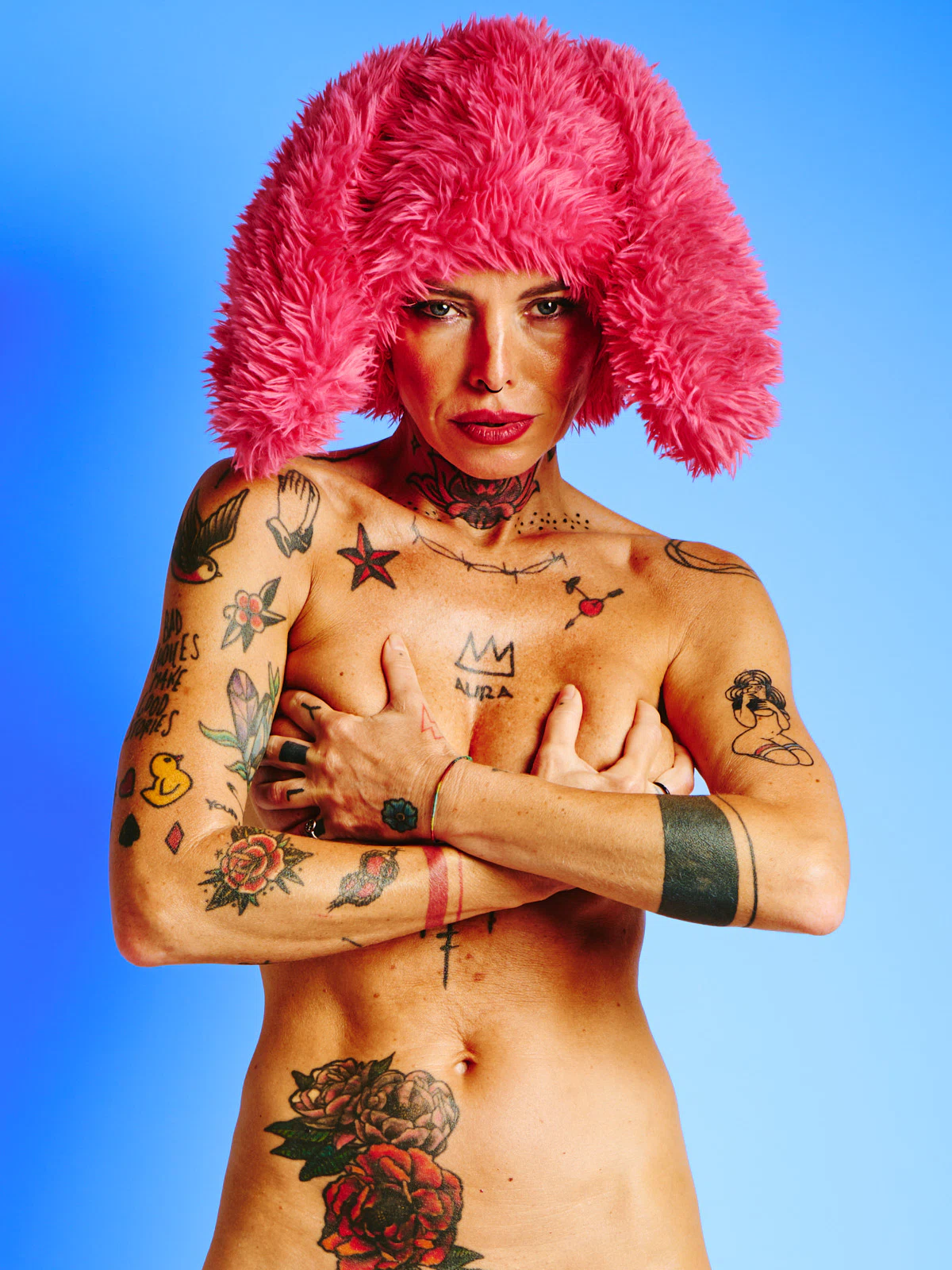 Tattooed nude model in the Red Rabbit series wearing red fur hat with rabbit ears