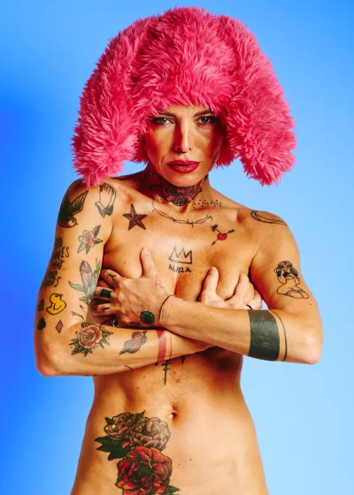 Tattooed nude model in the Red Rabbit series wearing red fur hat with rabbit ears