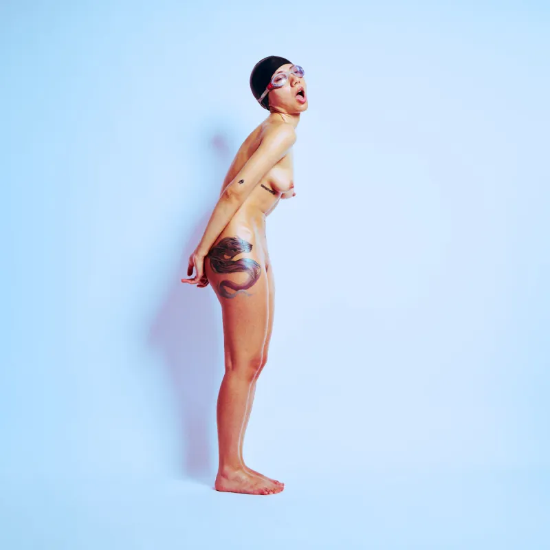 Artistic nude image of Kiki with water-covered skin and confident athletic pose.