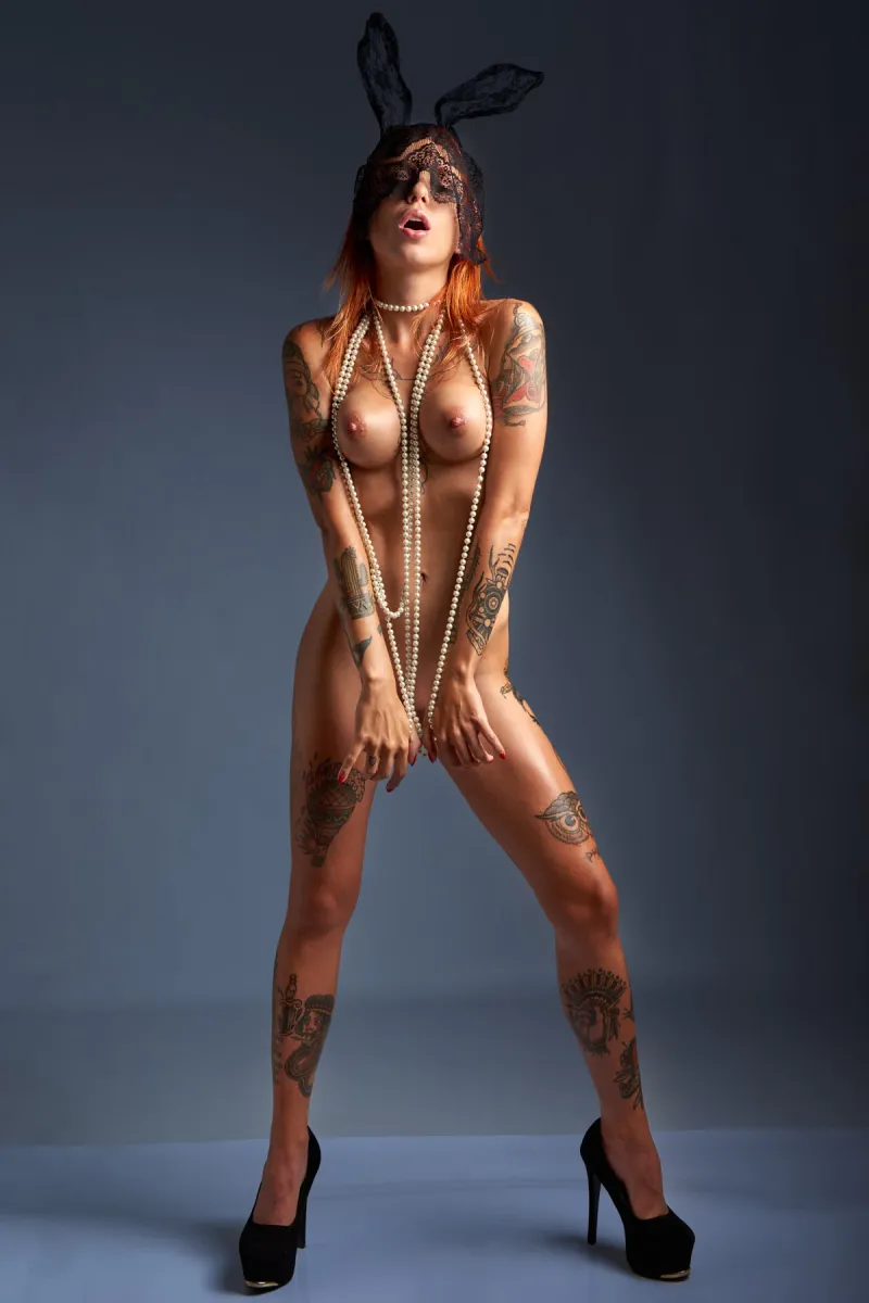 Ana Almeida nude wearing black lace rabbit ears, pearl necklace, and high heels.