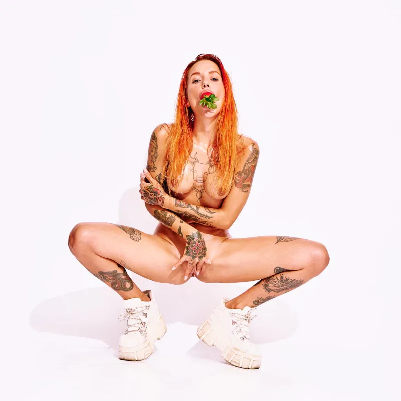 Tattooed red-haired model Ana Almeida in playful nude art photography.